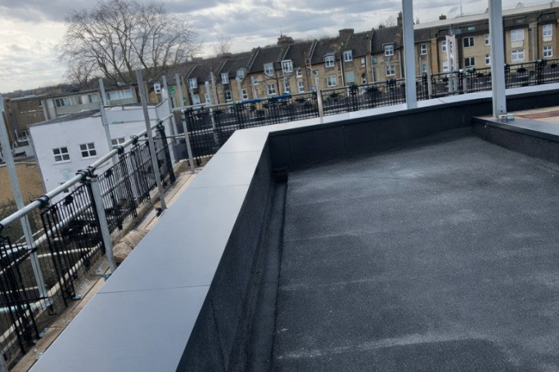 Aluminium coping along the edge of a rooftop with a view of residential buildings and a clear cityscape in the background.